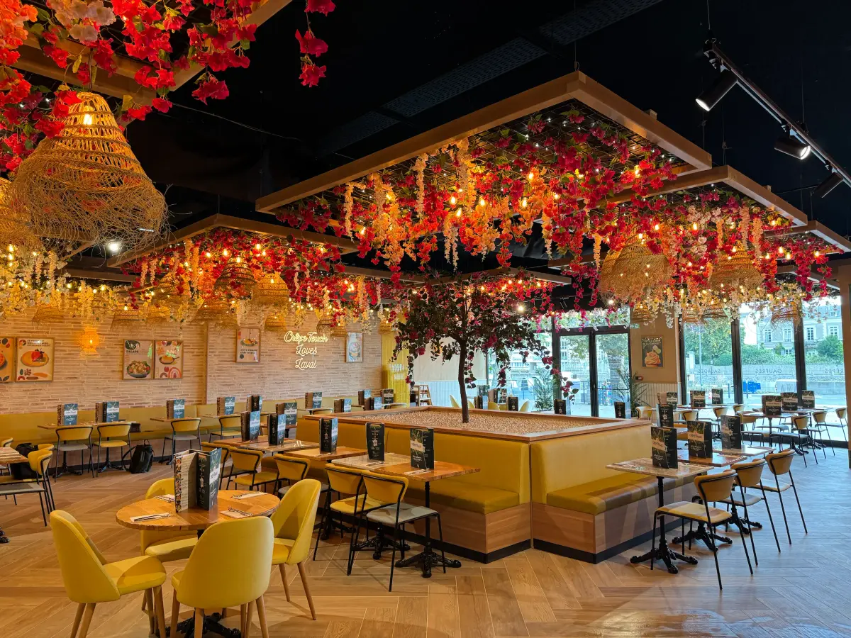 Vue panoramique de l'intérieur du restaurant avec fleurs suspendues et lumières chaudes