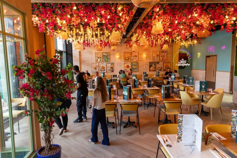 Salle du restaurant avec décoration florale suspendue, luminaires en osier et ambiance chaleureuse